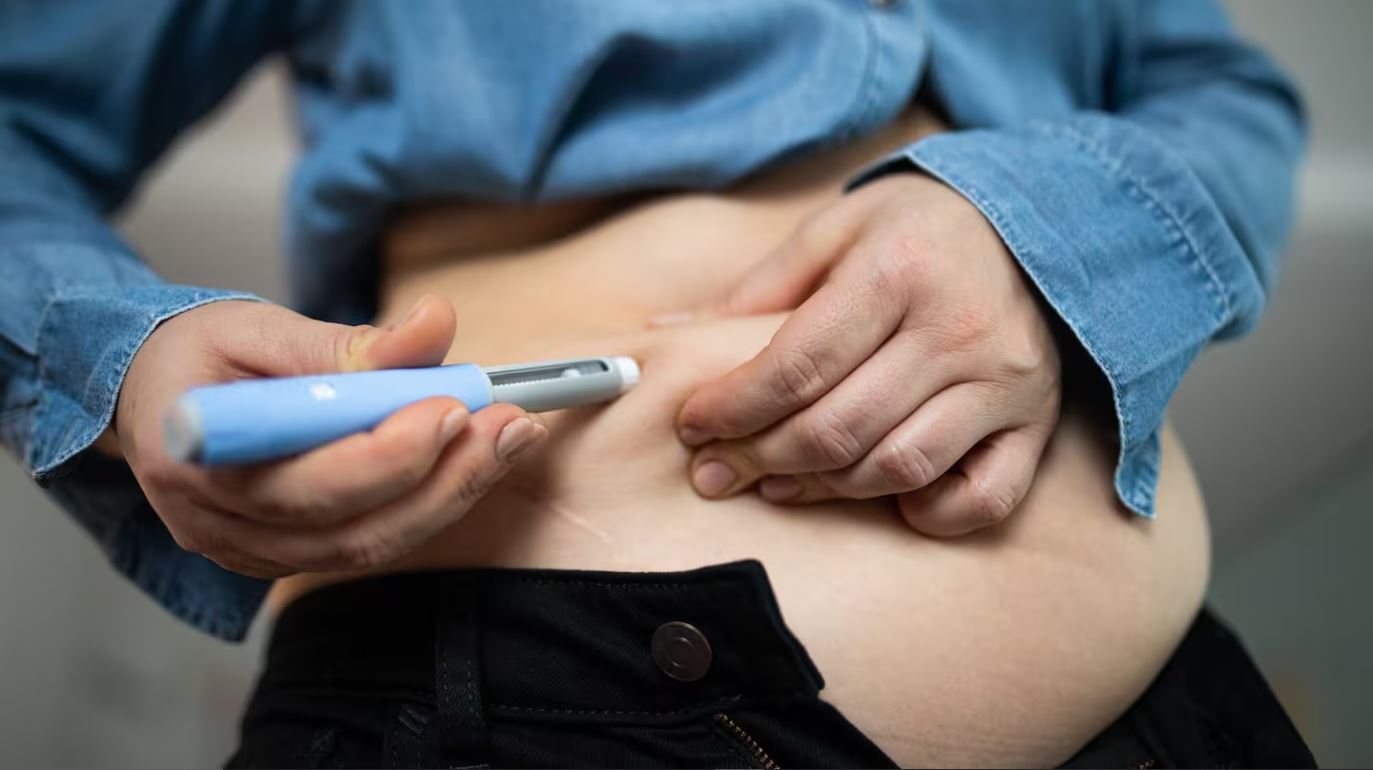 Person injecting GLP-1 weight loss medication like Ozempic into abdomen for diabetes or obesity treatment