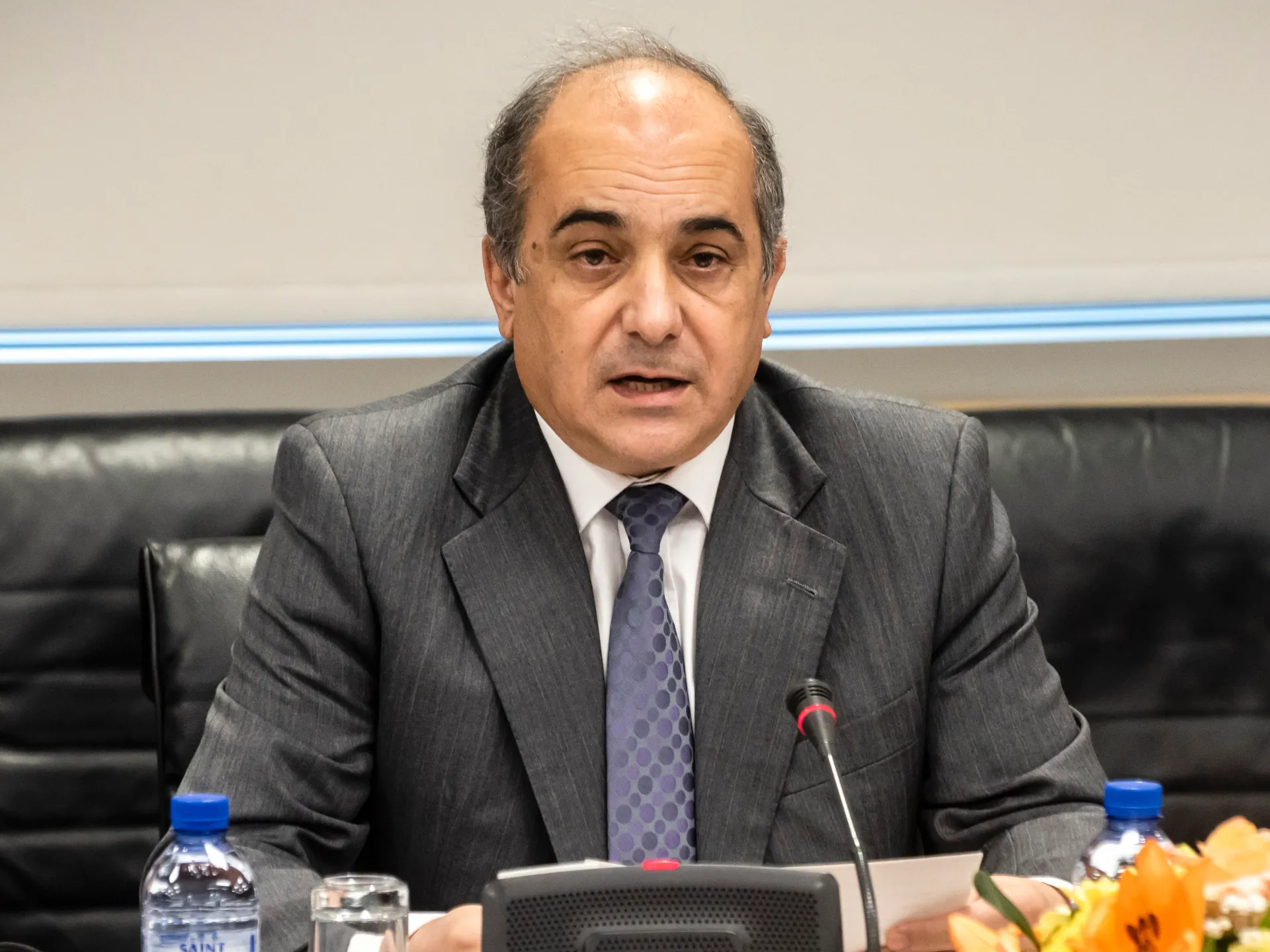 Demetris Syllouris speaking at a microphone during a parliamentary hearing