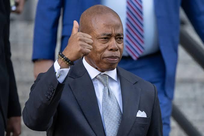 Eric Adams giving thumbs up outside court, bribery case dismissed