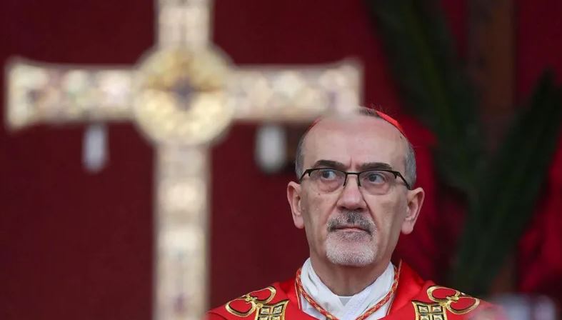 Latin Patriarch Cardinal Pierbattista Pizzaballa during a religious service, with a cross in the background symbolizing the significance of Holy Week in Jerusalem.