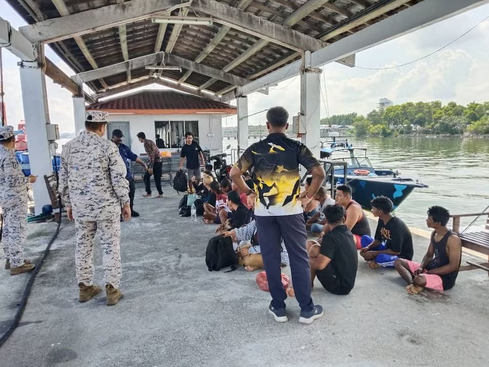Malaysian authorities and rescued Indonesian migrants gathered at a marine jetty after a boat capsized near Pangkor Island during a dangerous sea crossing.