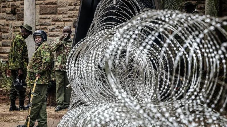 Kenyan security officers stand near coils of razor wire in Nairobi as authorities tighten security ahead of Gen Z protests.