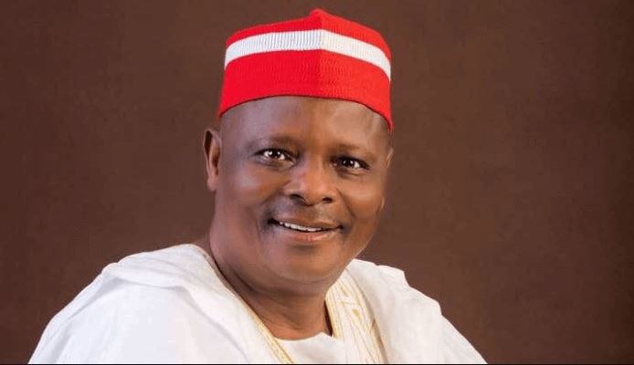 Rabiu Musa Kwankwaso smiling in a red traditional cap and white attire against a plain background