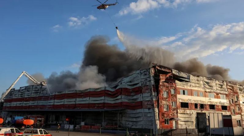 Smoke billows from a damaged building in Kyiv following a Russian missile attack as firefighters and a helicopter respond.