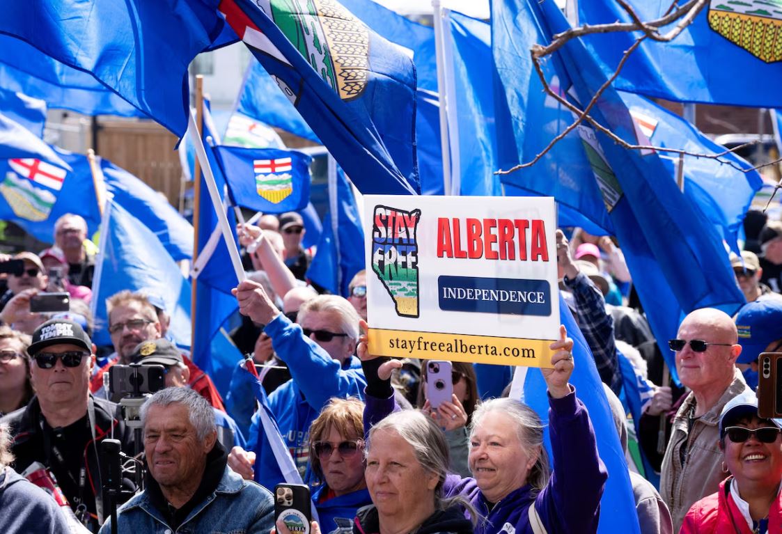 Crowd at an Alberta rally holding independence signs and Alberta flags during a demonstration on the province's separatist movement.