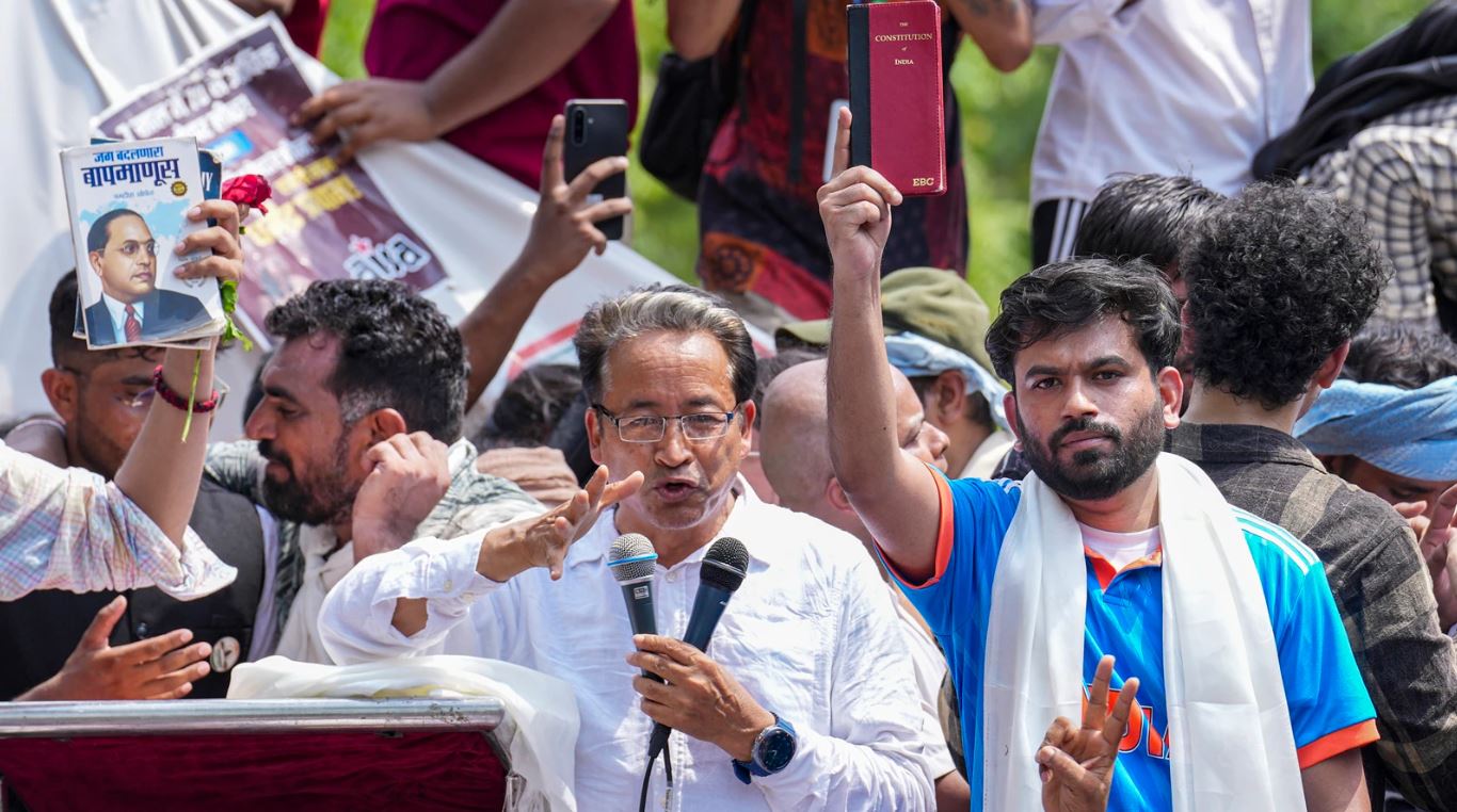 Crowd of protesters at Jantar Mantar holding the Indian Constitution and raising voices during a student-led demonstration with speakers addressing the gathering