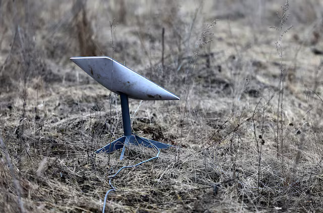 SpaceX Starlink satellite dish terminal standing in a dry grassy field in Ukraine.
