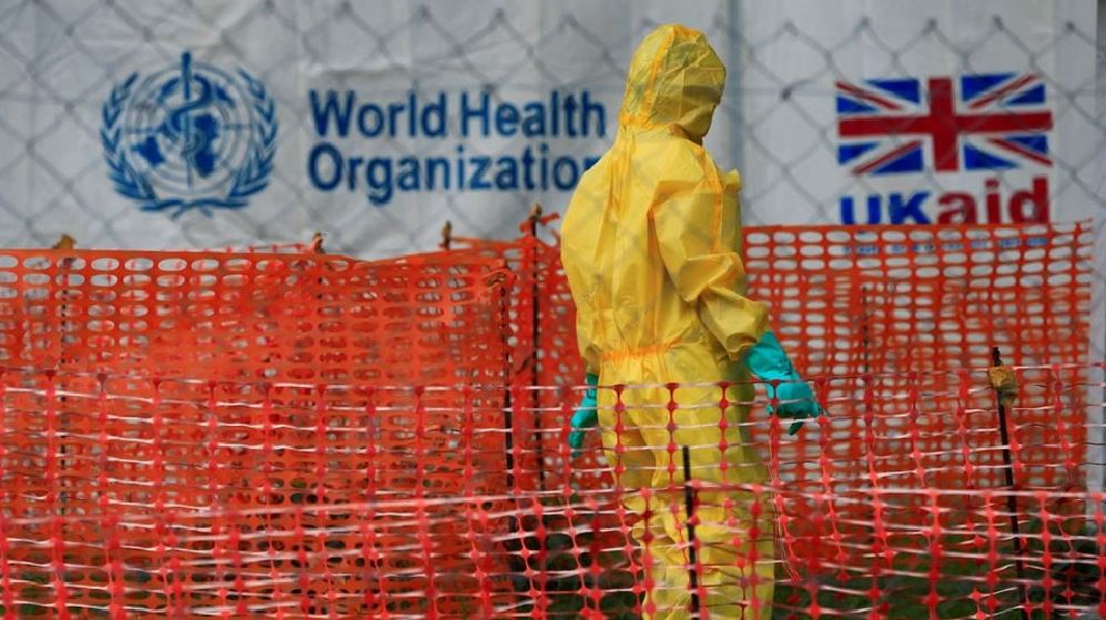 Healthcare worker in protective gear stands inside an Ebola containment zone during the WHO-declared global health emergency over the Bundibugyo outbreak in Congo and Uganda.